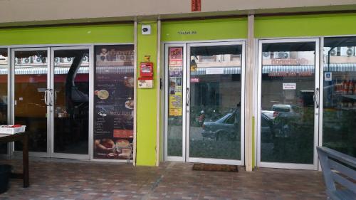 a green building with glass doors on a street at Natcha Place Rangsit Donmuang in Ban Talat Rangsit