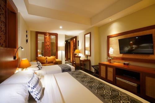 a hotel room with two beds and a flat screen tv at Kuta Seaview Boutique Resort in Kuta