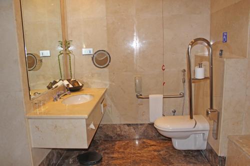 a bathroom with a toilet and a sink at Grand Regency Doha, Trademark Collection by Wyndham in Doha