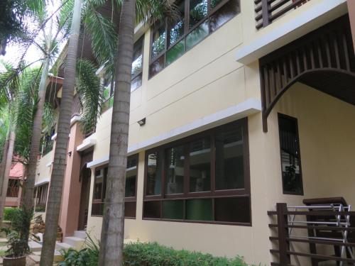 a building with palm trees in front of it at TandT House in Lamai