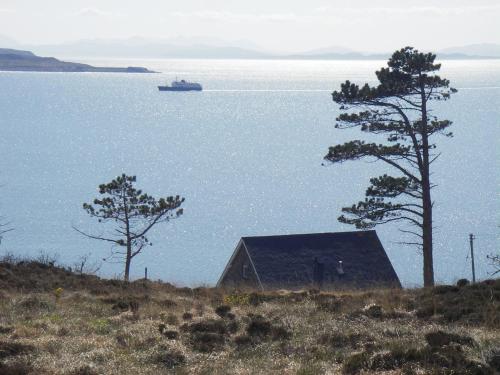 a house on a hill with a boat in the water at Gairloch Sands Youth Hostel in Gairloch