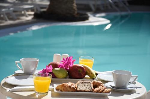 a tray of breakfast food on a table next to a pool at Arion Bay in Kamari