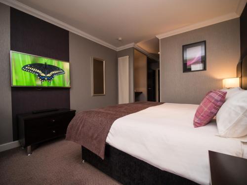 a hotel room with a large bed and a picture of a butterfly at Palace Hotel in Peterhead