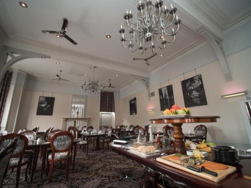 a dining room with tables and chairs and a chandelier at Palace Hotel in Peterhead