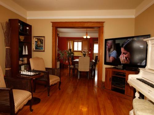 a living room with a television and a piano at Au Virage B&B in Magog-Orford