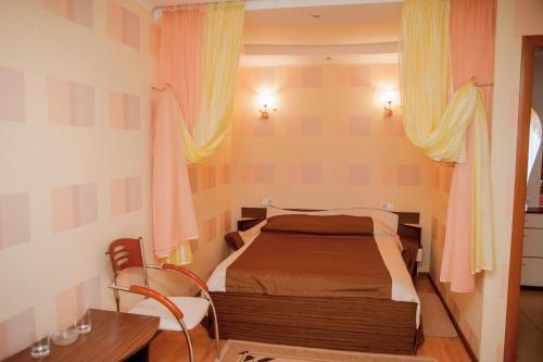 a bedroom with a bed and a desk and curtains at Dniprovski Zori in Kremenchuk