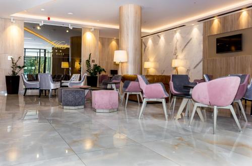 a hotel lobby with pink chairs and tables at Hotel Plaža Duće in Duće