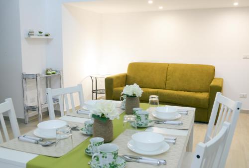 a dining room table with white dishes and a couch at Dimora Civitas Severiana in Montescaglioso