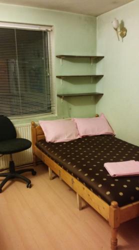 a bed in a room with a chair and a shelf at Къща за гости Пеневи in Sofia