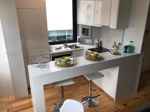 una cucina con bancone bianco e sgabelli di URBAN VIEWS Terrace - Duplex Apartment "Luis I" a Porto