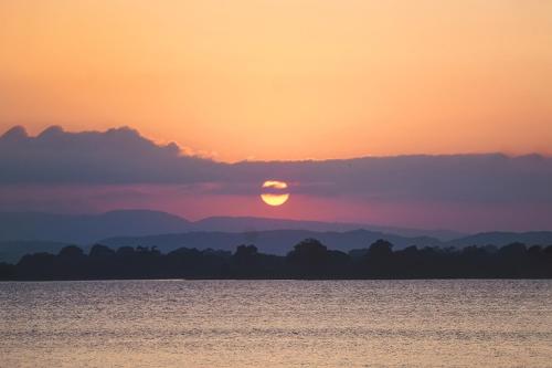 a sunset over a large body of water at Rivonway Hotel Polonnaruwa in Polonnaruwa