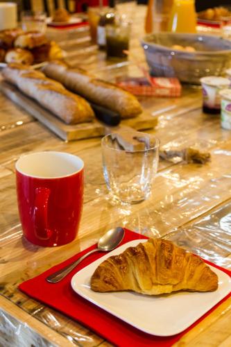 a table with a plate of bread and a spoon at Le Puy Carmin - Chambre d'hôtes avec jacuzzi in Bazoges-en-Paillers