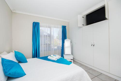 a bedroom with a bed with blue pillows and a tv at 2 on Bashee in Port Elizabeth