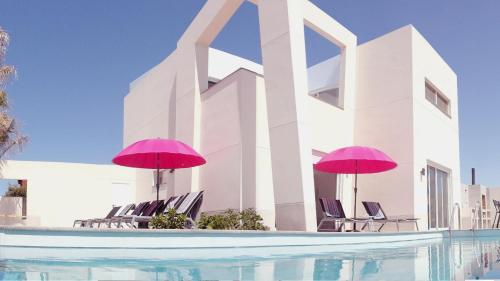 a pool with chairs and umbrellas next to a building at Villa Royale Trespalomas in Maspalomas