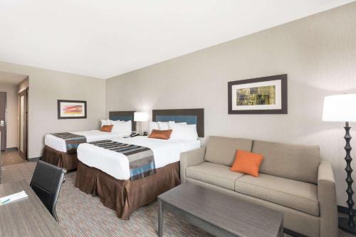 a hotel room with a bed and a couch at Wingate by Wyndham Lubbock in Lubbock