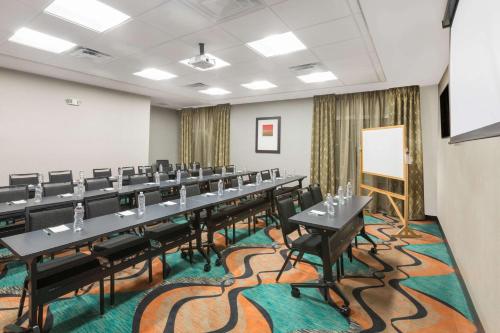 a conference room with tables and chairs and a whiteboard at Wingate by Wyndham Lubbock in Lubbock