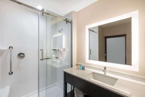 a bathroom with a sink and a shower with a mirror at Wingate by Wyndham Lubbock in Lubbock