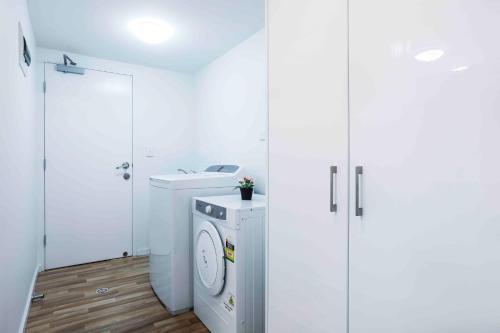 a white bathroom with a washing machine and a sink at Sandbox Apartments in Gold Coast