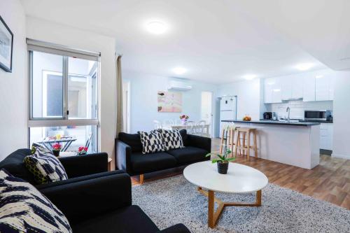 a living room with two couches and a table and a kitchen at Sandbox Apartments in Gold Coast