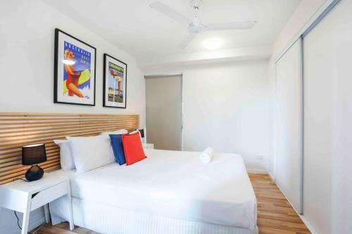 a white bedroom with a white bed and a desk at Sandbox Apartments in Gold Coast