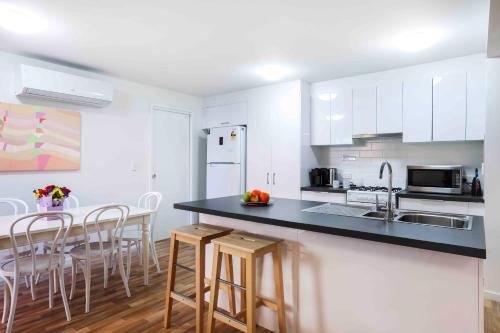a kitchen with white cabinets and a black counter top at Sandbox Apartments in Gold Coast