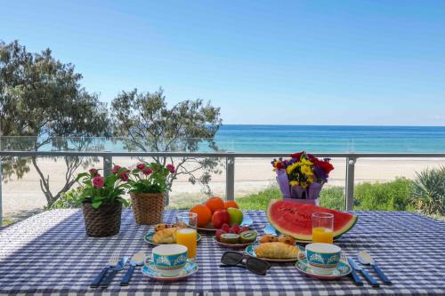 a picnic table with food and a view of the beach at Sandbox Apartments in Gold Coast