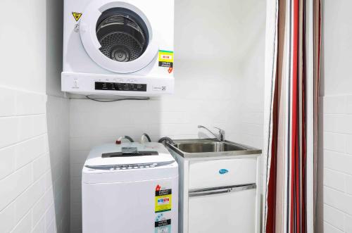 a kitchen with a sink and a washing machine at Sandbox Apartments in Gold Coast