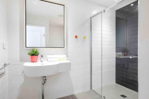 a white bathroom with a sink and a shower at Sandbox Apartments in Gold Coast
