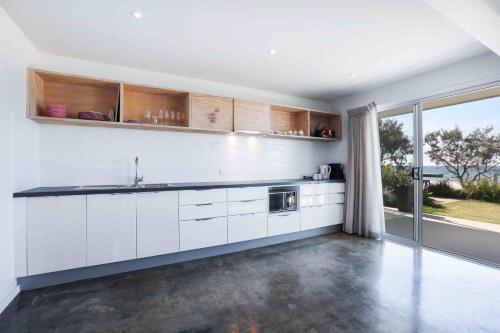 a kitchen with white cabinets and a large window at Sandbox Apartments in Gold Coast
