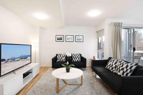 a living room with a black couch and a tv at Sandbox Apartments in Gold Coast