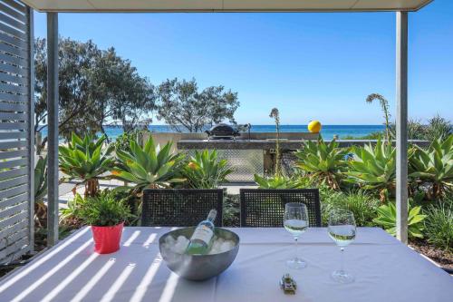 a table with wine glasses and a view of the ocean at Sandbox Apartments in Gold Coast