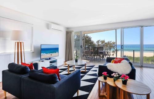 a living room with a couch and chairs and a television at Sandbox Apartments in Gold Coast