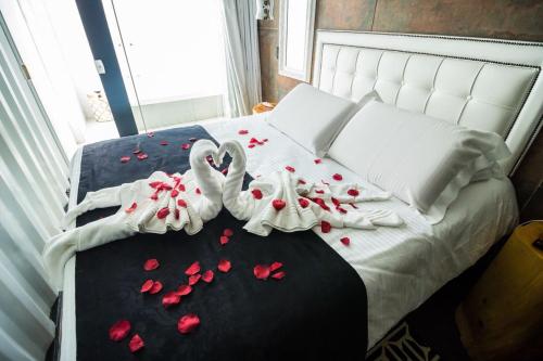 two swans are laying on a bed covered in rose petals at Pousada Cafe Poesia in Campos do Jordão