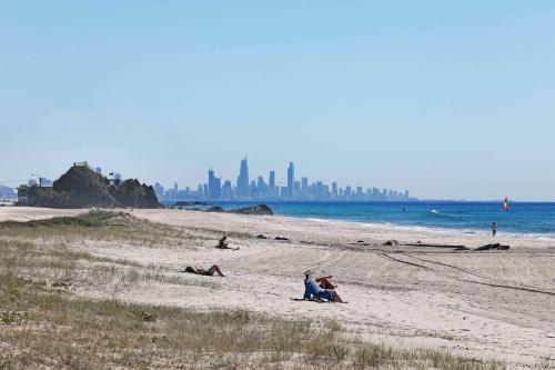 people sitting on a beach with a city in the background at Sandbox Apartments in Gold Coast