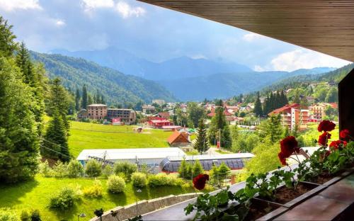 a view of a town from a balcony with flowers at Lux Garden Hotel in Azuga