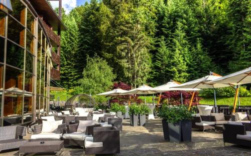 a patio with chairs and tables and umbrellas at Lux Garden Hotel in Azuga