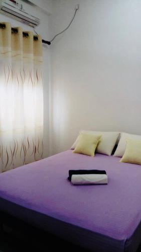 a bedroom with a bed with purple sheets and a window at The City Tourist Hotel in Anuradhapura