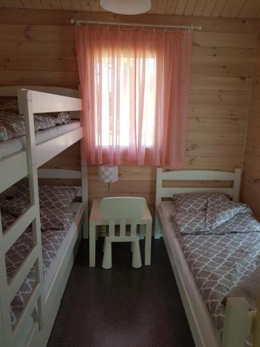 a bedroom with two bunk beds and a table at Domki Siódme Niebo in Stegna