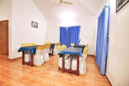 a group of tables and chairs in a room at Wayanad Three Roots Holiday Home Resort in Sultan Bathery