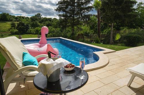a patio with a table and a pool with a drink at Villa Palma Karojba in Karojba