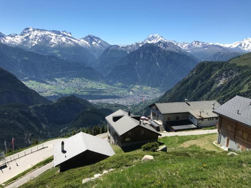 a group of buildings on a hill with mountains in the background at Augusta in Belalp