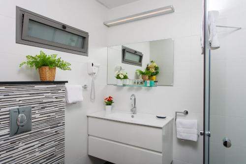 a white bathroom with a sink and a shower at Out of Africa Resort in Had Nes