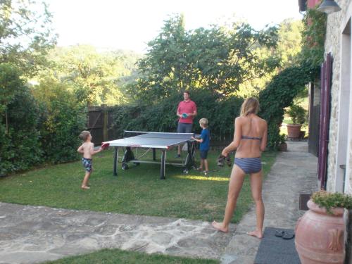 a woman and two children playing a ping pong table at Agriturismo Campo del Pillo in Pietradura