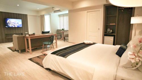 a bedroom with a large white bed and a desk at The Lake Udon in Udon Thani