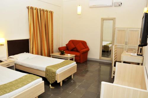 a hotel room with two beds and a red chair at Shanthiniketan - Ramoji Film City in Pedda Ambarpet