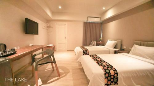 a hotel room with two beds and a desk at The Lake Udon in Udon Thani