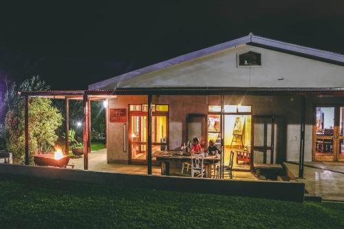 a house with people sitting at a table outside at night at A Hilltop Country Retreat in Swellendam