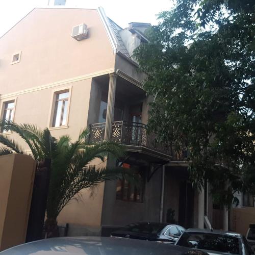 a house with a balcony and cars parked in front of it at NaNa's Guesthouse in Batumi