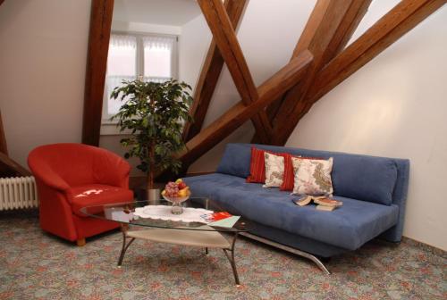 a living room with a blue couch and a red chair at Hotel Zur Krone in Beilngries