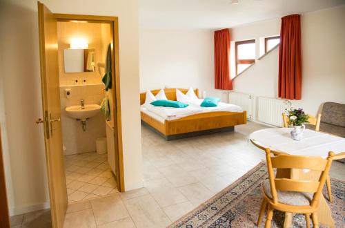 a hotel room with a bed and a table and a bathroom at Hotel Janssen in Bodenheim
